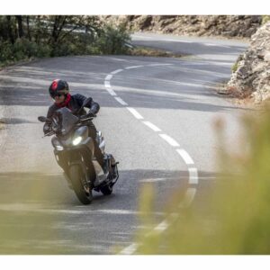 Motorrad auf einer kurvenreichen Straße Ein Motorradfahrer auf einer kurvenreichen Straße. Der Fahrer trägt einen schwarzen Helm und eine schwarze Jacke.