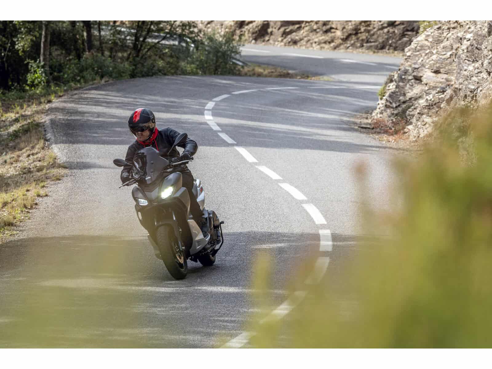 Motorrad auf einer kurvenreichen Straße Ein Motorradfahrer auf einer kurvenreichen Straße. Der Fahrer trägt einen schwarzen Helm und eine schwarze Jacke.
