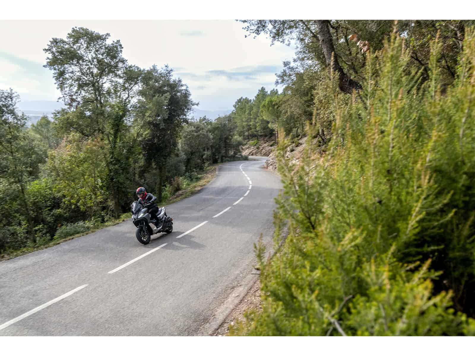 Motorradfahrer auf einer kurvenreichen Landstraße Ein Motorradfahrer fährt auf einer kurvenreichen Straße durch eine grüne Landschaft. Der Fahrer trägt Schutzkleidung.